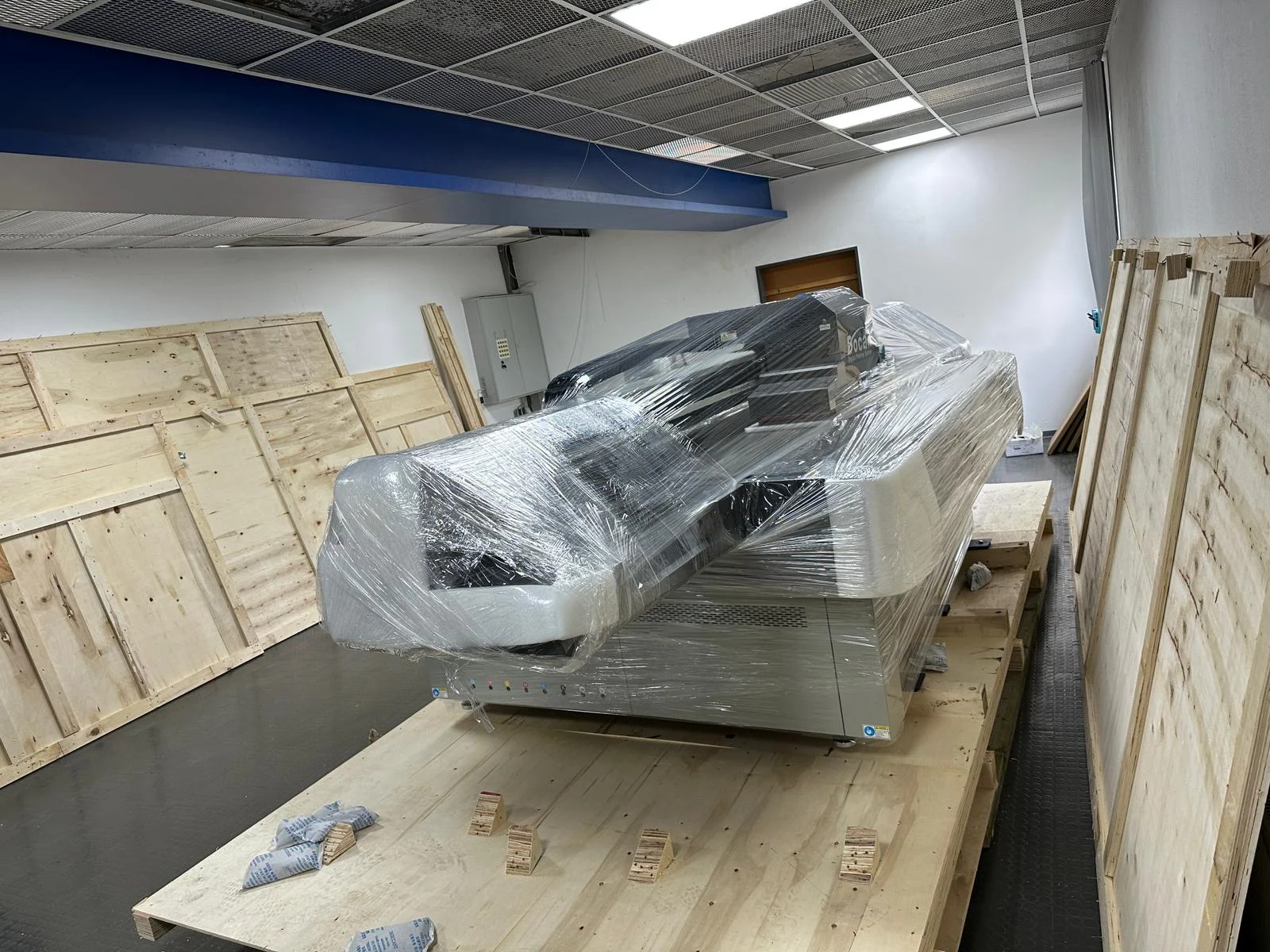Ein großer Flachbettdrucker wird aus einer Transportkiste ausgepackt